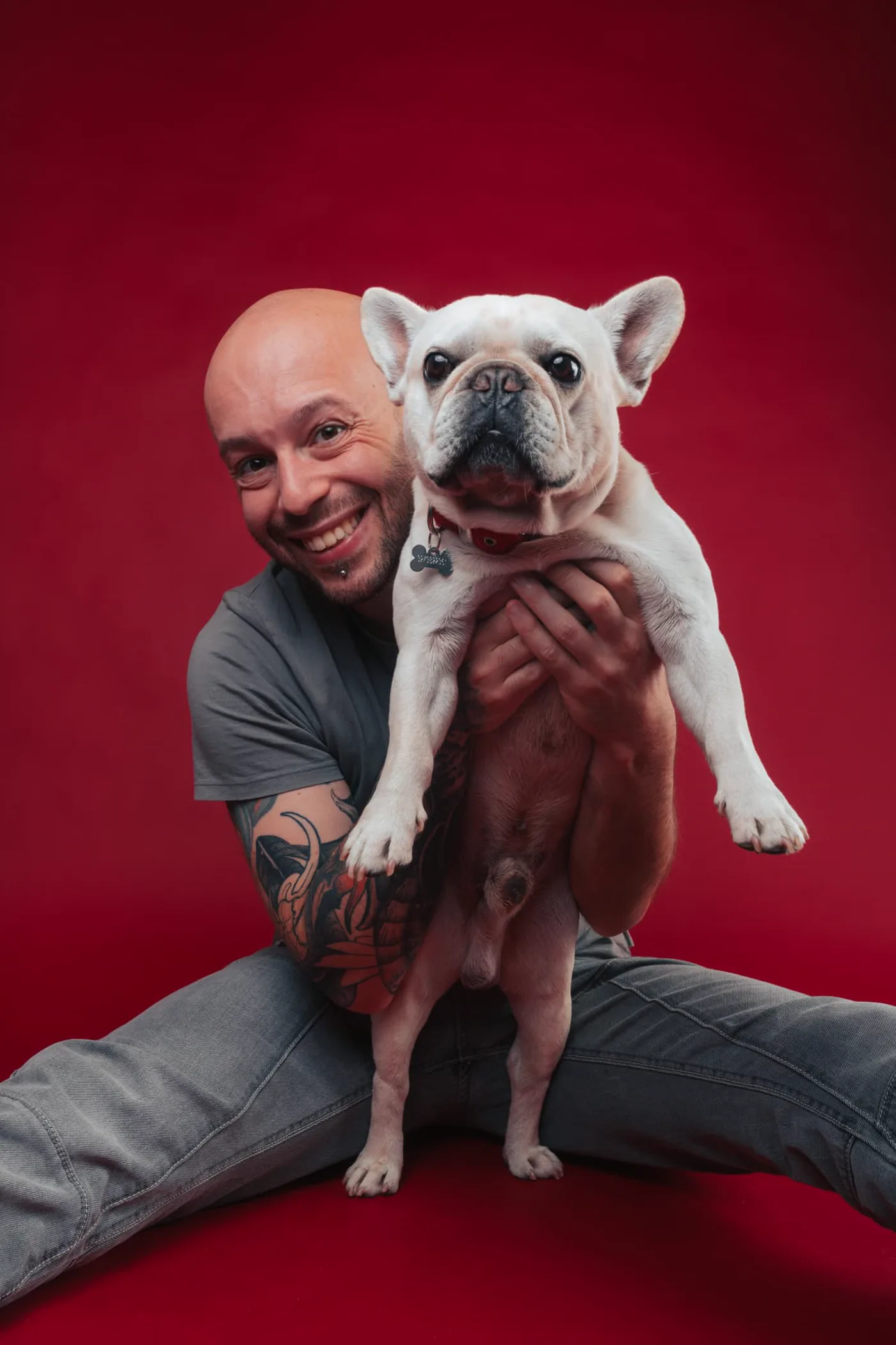 Andrea Agati, fotografo di pet photography, ritratto in studio con un bulldog francese su sfondo rosso